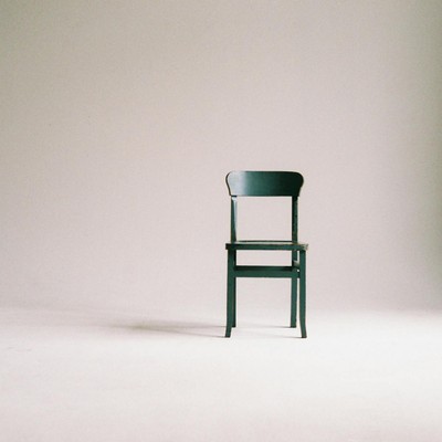 A single black chair in a minimalistic studio setting with a neutral backdrop.